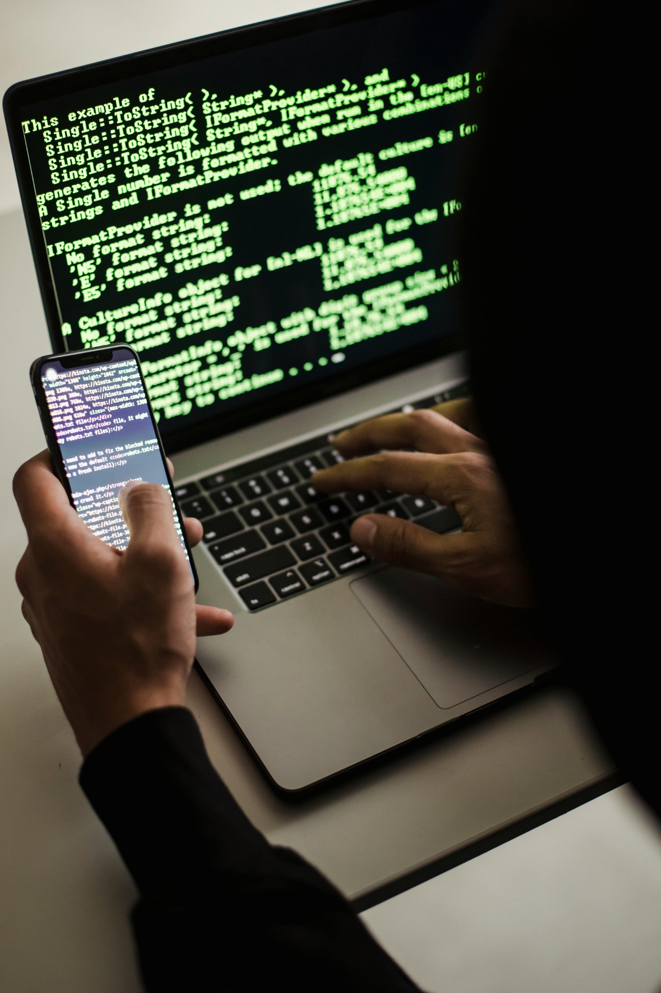 Phone and laptop with code on screen — IP theft and trade-secret tracing